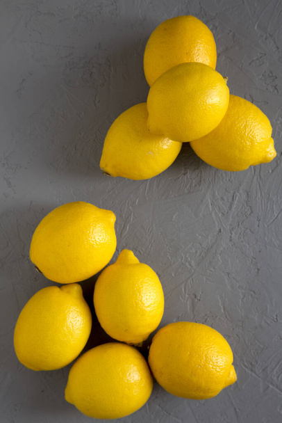 Свежие спелые желтые органические лимоны на серой поверхности, вид сверху. Плоская квартира
 - Фото, изображение