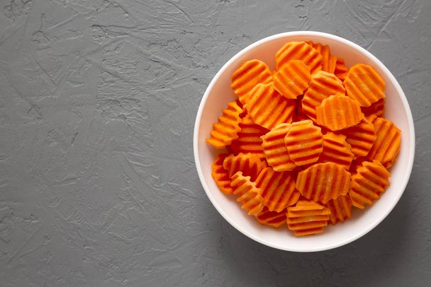 Friss nyers bio sárgarépa Chips egy fehér tál felett szürke backgro - Fotó, kép