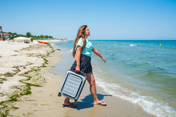 Hermosa chica con una bolsa en una playa. hermosa adolescente corriendo con maleta, arena blanca, destino de equipaje trópico. - Foto, imagen