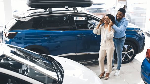 Marido cobrindo Esposas Olhos Mostrando Novo Carro Em Auto Dealership
 - Foto, Imagem