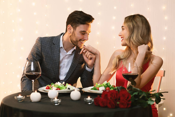 Romántico hermosa pareja comedor en restaurante, hombre cariñoso besar novias mano
 - Foto, imagen