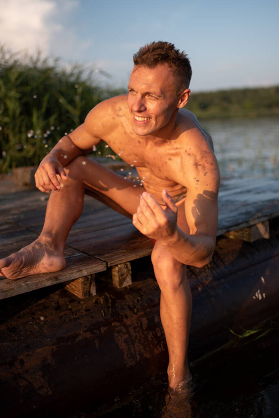 Homme athlétique sur le lac. Assieds-toi sur le quai
. - Photo, image