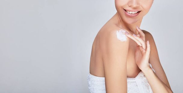 The girl after the shower puts body cream on her shoulder. - Foto, Imagem