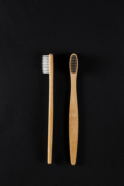 Eco-friendly bamboo toothbrushes against a dark background. - Foto, Bild