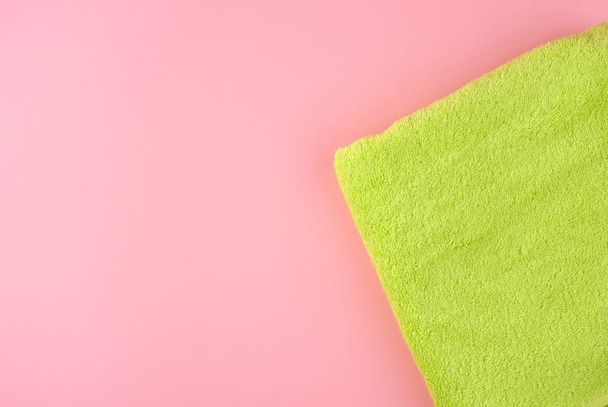 πράσινο βαμβάκι terry πετσέτα διπλωμένο σε ροζ φόντο, πάνω όψη - Φωτογραφία, εικόνα