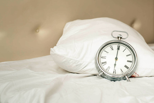 Alarm clock on white bad for wak up time with light - 写真・画像