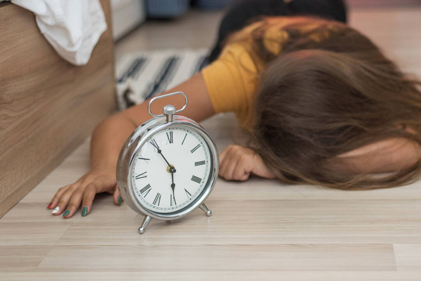 Sleepy young woman trying kill alarm clock . Early wake up, not getting enough sleep, getting work concept. Female stretching hand to ringing alarm willing turn it off - Fotoğraf, Görsel