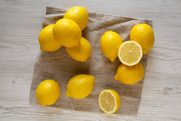 Созревшие желтые органические лимоны на белом деревянном столе, вид сверху. Fl
 - Фото, изображение