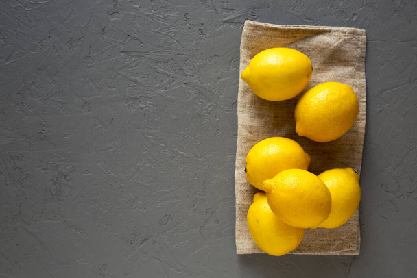 Rijp gele biologische citroenen op grijs oppervlak, bovenaanzicht. Vlakke plaat,  - Foto, afbeelding