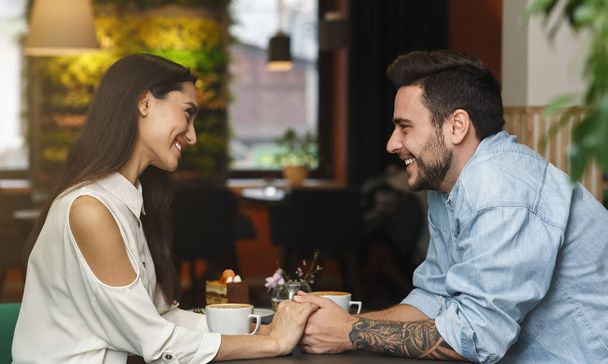 Прекрасна пара фліртувати і розмовляти тримаючи руки сидячи в кафе
 - Фото, зображення