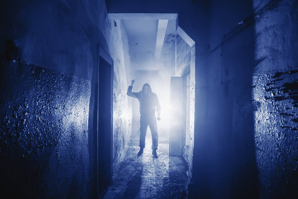 Niebezpieczny Morderca lub zabójca z nożem w ręku i światło z tyłu w strasznym korytarzu w kolorze Phantom Blue stonowane - Zdjęcie, obraz
