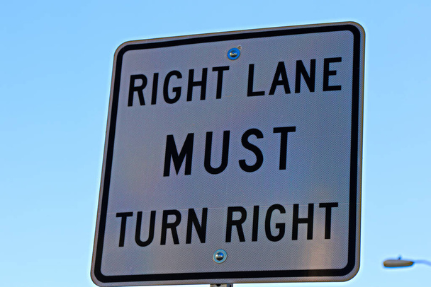 Señal de carril derecho debe girar a la derecha fondo de color blanco. carril derecho gira a la derecha por delante signo de color blanco en la calle principal de EE.UU. Señales e instrucciones para los conductores, peatones y transeúntes.
" - Foto, imagen