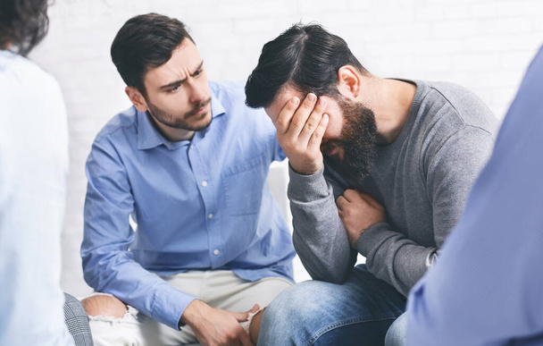Membres du groupe réconfortant un homme toxicomane en pleurs lors d'une séance de réadaptation
 - Photo, image