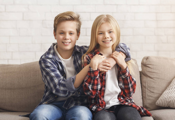 słodkie chłopiec i dziewczyna przytulanie siedzi na kanapie w domu - Zdjęcie, obraz