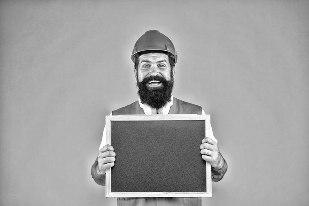 Warranty service. Handsome repairman. Man bearded repairman builder work clothes. Responsibility and garanties. Engineering and architect occupation. Repairman engineer hold blackboard copy space - Photo, Image