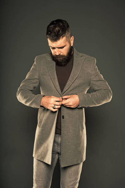 Dressing as fashionable man. Fashionable look of vogue model on grey background. Bearded man buttoning fashionable jacket. Fashionable hipster wear casual style - Valokuva, kuva