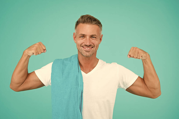 Healthy lifestyle. Gym wear and sports fashion for men. Gym aesthetics. Man well groomed athlete with towel on blue background. Mature but still in good shape. Exercising in gym for better health - Foto, afbeelding