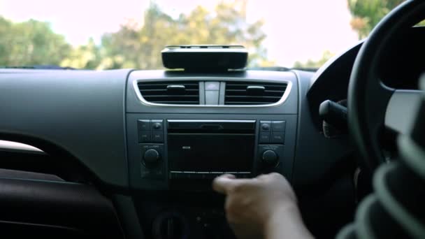 Jonge vrouw rijden een auto en draai-knop van de radio in de auto op zonnige dag. - Video