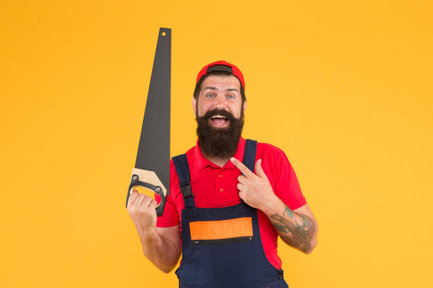 carry out repairs. build and construction. Skilled architect repair and fix. engineer worker career. brutal male worker with saw. man builder yellow background. professional repairman in uniform - Foto, afbeelding