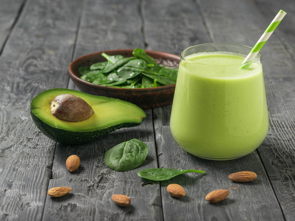 A drink of avocado, spinach and almond milk on a dark wooden table. Fitness product. - Valokuva, kuva