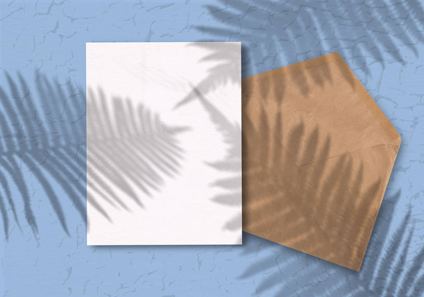 Φάκελος με ένα φύλλο χαρτί σε μπλε φόντο. Mockup με επικάλυψη των σκιών των φυτών. Το φυσικό φως ρίχνει μια σκιά από ψηλά. - Φωτογραφία, εικόνα