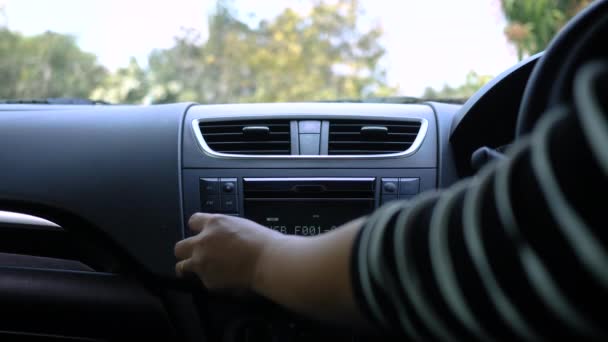 Nuori nainen ajaa autoa ja kääntämällä painiketta radio autossa aurinkoisena päivänä
. - Materiaali, video