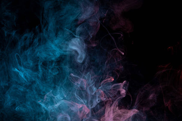 Товстий барвистий дим червоного, синього кольору на чорному ізольованому тлі. Тло з диму вейпу
 - Фото, зображення