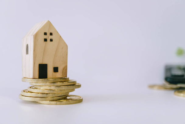 Міні-модель будинку на золотій монеті з чистим білим копійчастим тлом. Економія інвестиційної нерухомості
. - Фото, зображення