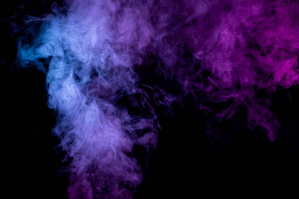 Thick colorful smoke of pink, blue on a black isolated background. Background from the smoke of vape - Photo, image