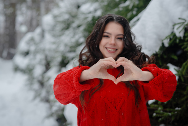 冬の公園で赤いセーターを着た若い美しい女の子。. - 写真・画像