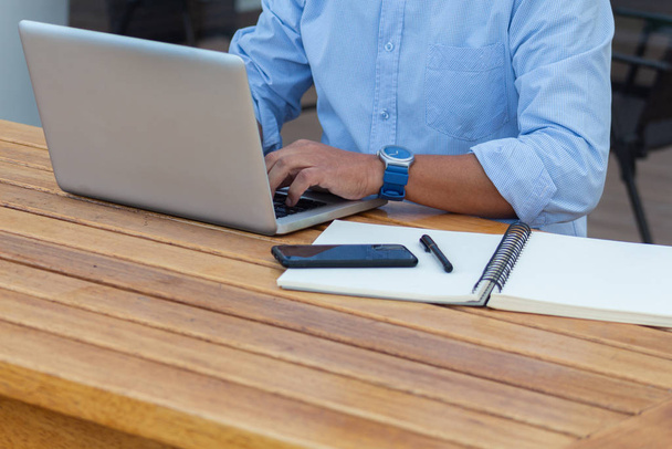 En una oficina de coworking un hombre trabaja con su portátil en un escritorio de madera
 - Foto, Imagen