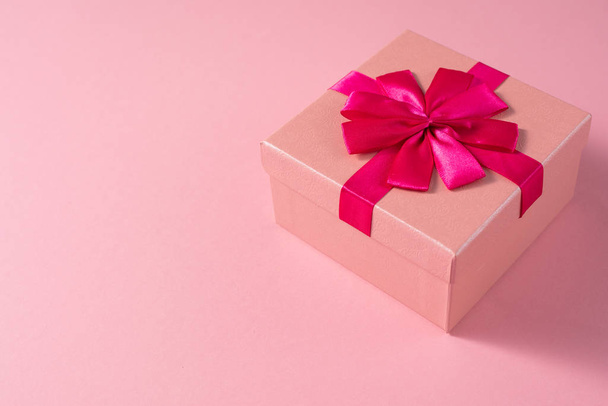 Valentine's Day celebration concept. A nice gift from a loved one. Box with a bow on a delicate pink background. Copy space. Flat lay. Close-up. - Foto, Imagen