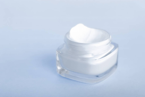 Face cream moisturizer jar on blue background, moisturizing skin - Photo, image