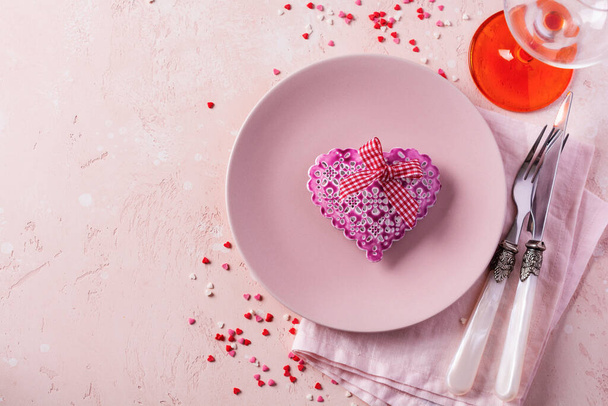 Valentines day table setting with pink plate and gift heart on pink light background. - Фото, изображение