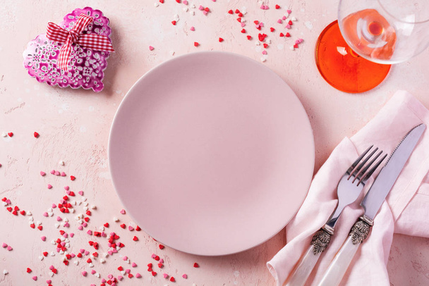 Valentines day table setting with pink plate and gift heart on pink light background. - Foto, afbeelding