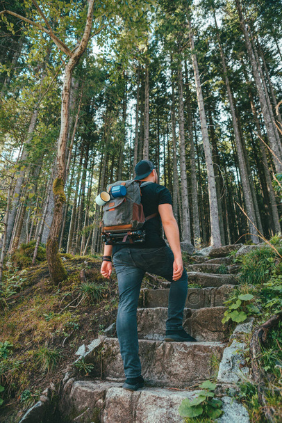 man met rugzak die via stenen trappen naar het bos loopt - Foto, afbeelding