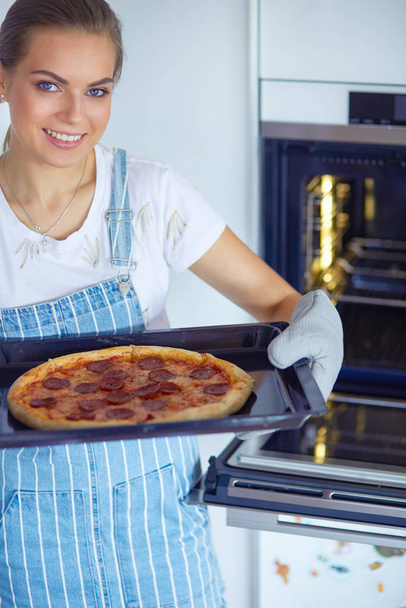 Happy young woman cooking pizza at home - Foto, afbeelding