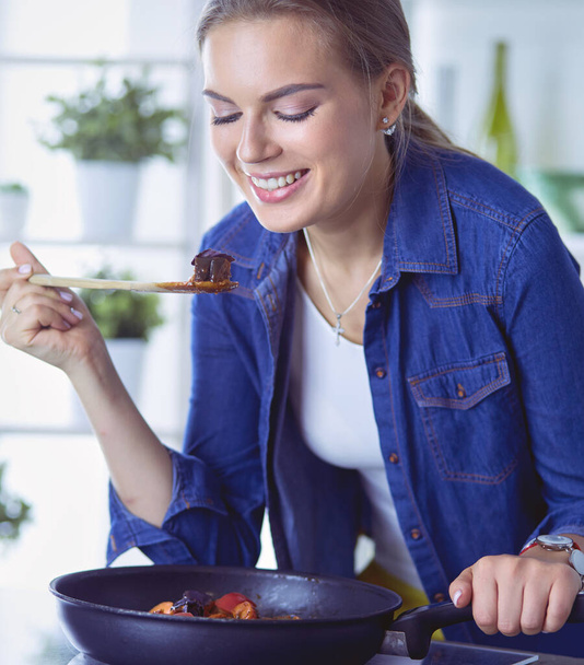 Young woman cooking healthy food holding a pan with vegetables is it. Healthy lifestyle, cooking at home concept - Foto, Bild