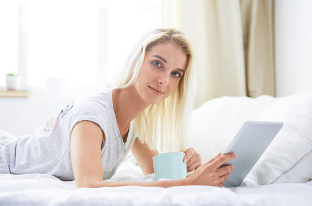 Girl holding digital tablet with blank screen and smiling at camera in bedroom - Foto, Imagen