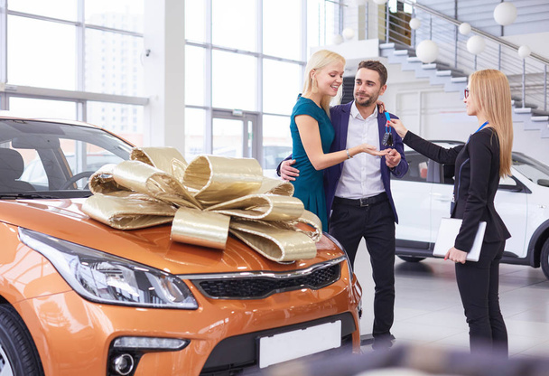 A man makes a gift - a car to his wife. She is surprised at this. They are very happy about - Фото, зображення