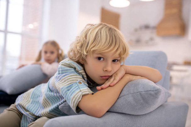 Blond cute boy with a pillow in his hands looking unhappy - Fotoğraf, Görsel