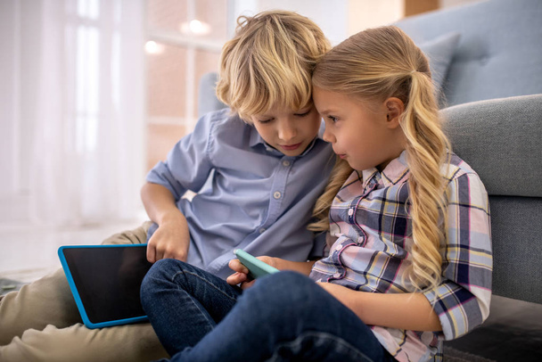 Boy and girl watching something on tablet and discussing - Фото, зображення