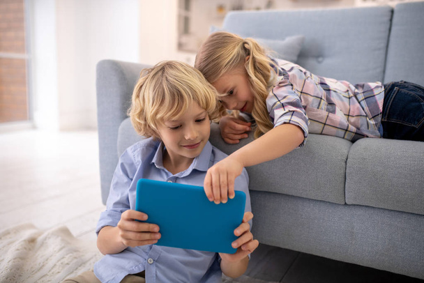 Boy and girl holding tablet together, watching something, smiling - Fotografie, Obrázek