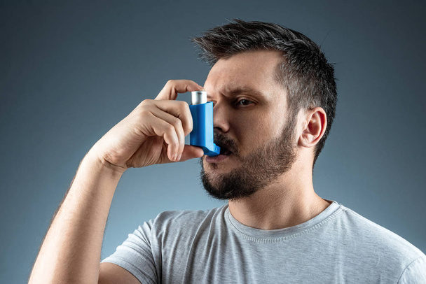 Muotokuva miehestä, jolla on astma-inhalaattori käsissään, astmakohtaus. Keuhkoastman, yskän, allergioiden, hengenahdistuksen hoidon käsite
. - Valokuva, kuva