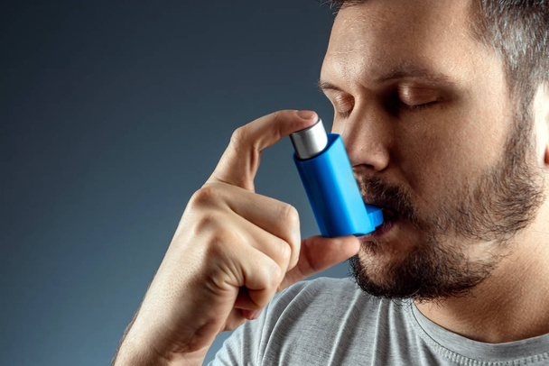 Portrait of a man with an asthma inhaler in his hands, an asthmatic attack. The concept of treatment of bronchial asthma, cough, allergies, dyspnea. - Fotoğraf, Görsel
