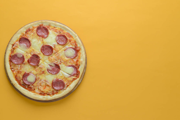Flat lay pepperoni pizza isolated on bright yellow background. Pizza salami cut in slices. Fast food, junk food concept. - Fotografie, Obrázek