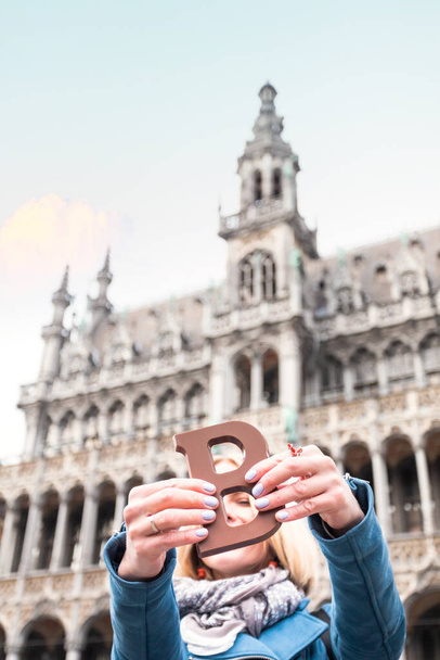 Woman with milk chocolate bar standing on the Grand place in Brussels in Belgium. - Foto, Imagem