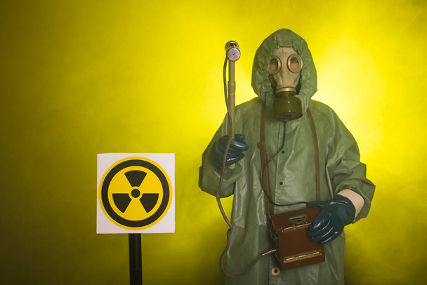 Promieniowanie, zanieczyszczenie i koncepcja zagrożenia - człowiek w odzieży ochronnej i masce gazowej na ciemnym tle - Zdjęcie, obraz