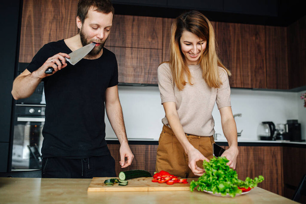 Couple at home slicing vegetables for a salad. - Foto, afbeelding