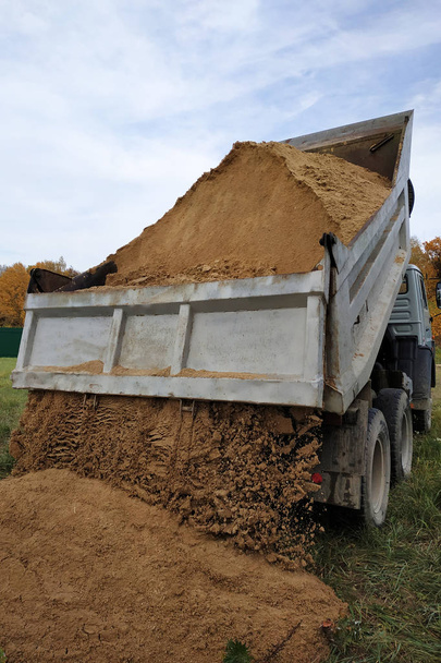 A dump truck unloads sand in the construction site. - 写真・画像